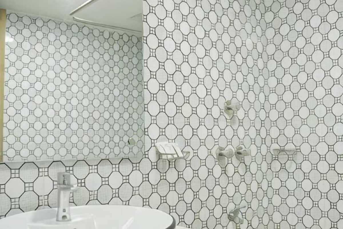 Un baño con un patrón de azulejos hexagonales, un lavabo blanco y un espejo.