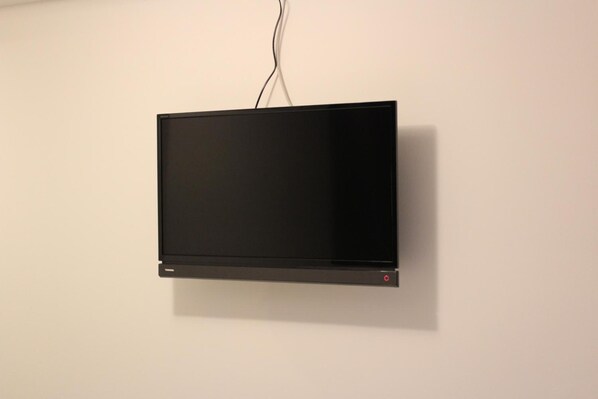 A flat-screen TV mounted on a plain wall with a visible power cord.