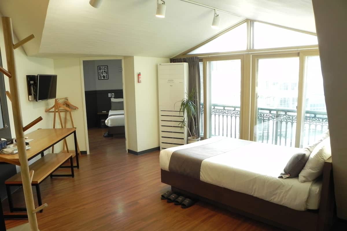 A hotel room with a bed, a desk, a chair, a TV, and a balcony with a view.