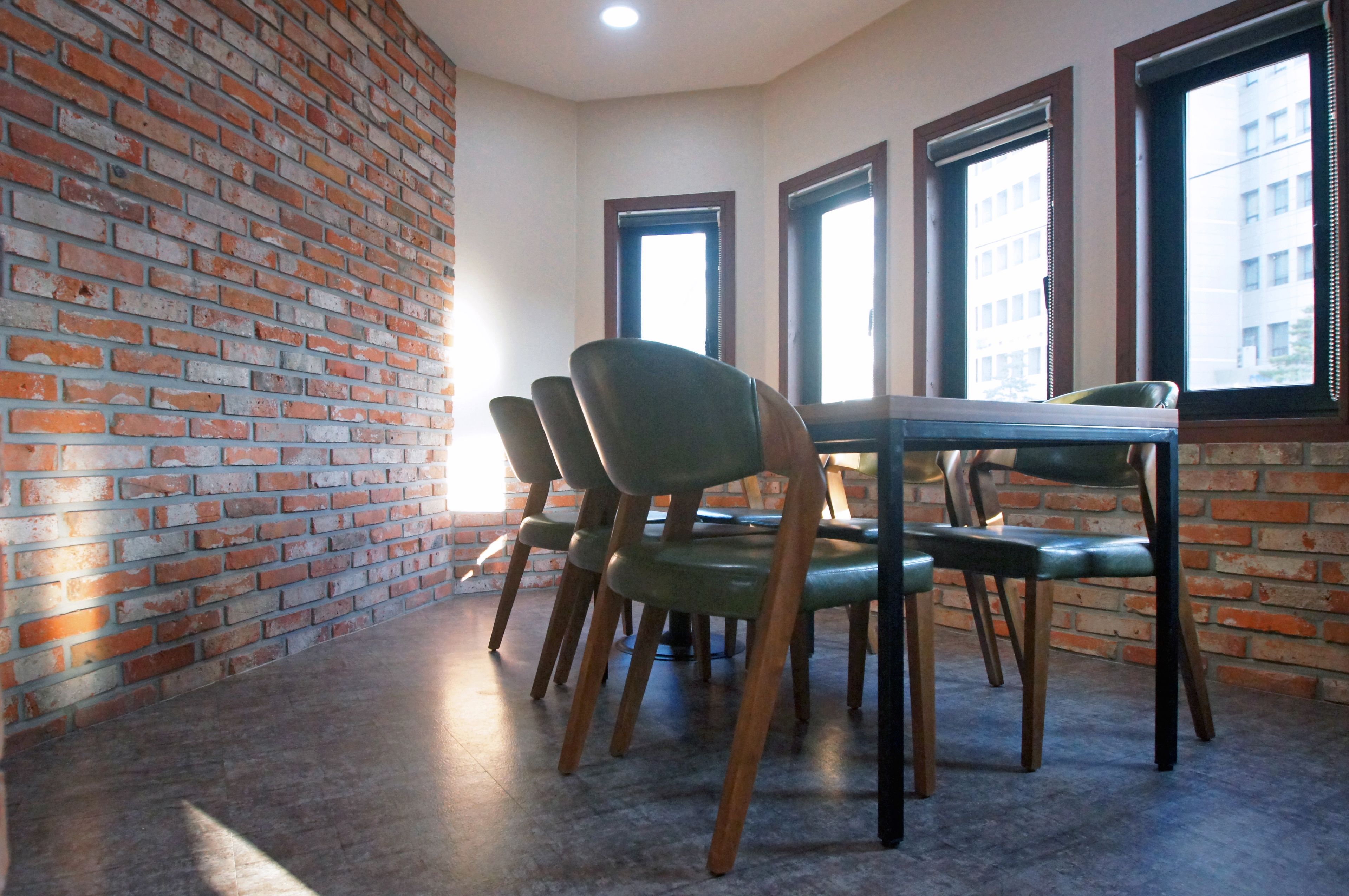Comedor con paredes de ladrillo, una mesa y cuatro sillas.