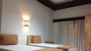 A hotel room with two single beds, a wooden headboard, a wall-mounted light fixture, and a window with curtains. - Kubu B'dauh Homestay (Legian)