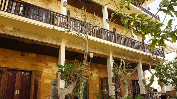 A multi-story building with balconies, wooden railings, and a mix of stone and wood textures. - Kubu B'dauh Homestay (Legian)