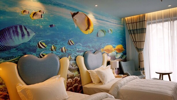 A hotel room with two beds, a mural of tropical fish, and a view of the ocean through the window. - Metropolo Jinshanzui Village Hotel (Shanghai)