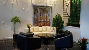 A modern living room with a sofa, two armchairs, a coffee table, and decorative plants. - Metropolo Jinshanzui Village Hotel (Shanghai)