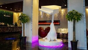 A modern lobby with a reception desk, a unique white sculpture, and two potted plants. - Metropolo Jinshanzui Village Hotel (Shanghai)