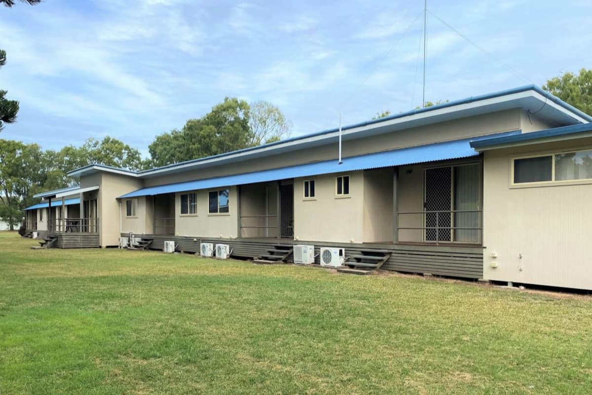 A row of single-story buildings with a flat roof, each with a covered porch and air conditioning units.
