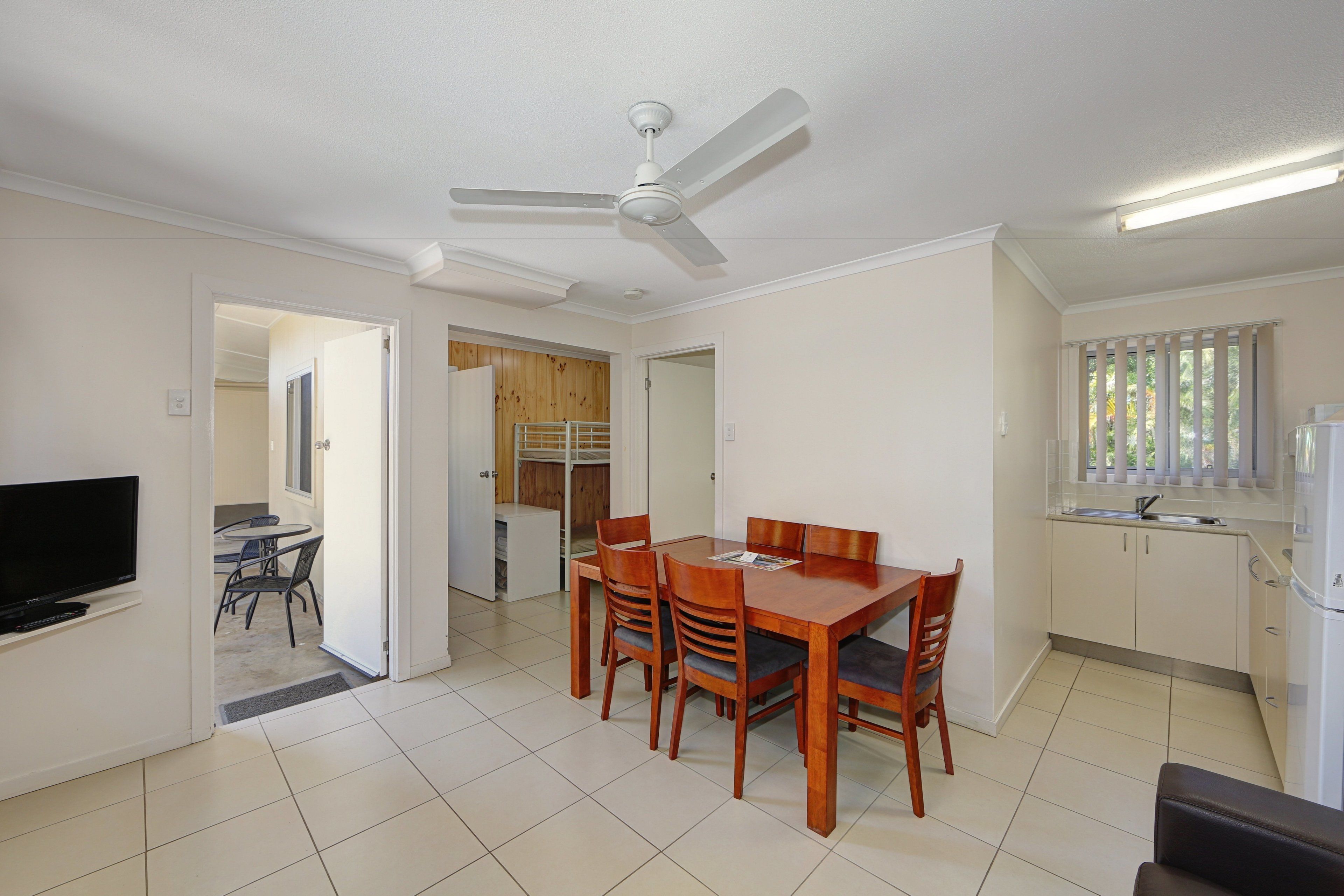 A compact living space with a dining area, kitchenette, and a TV.