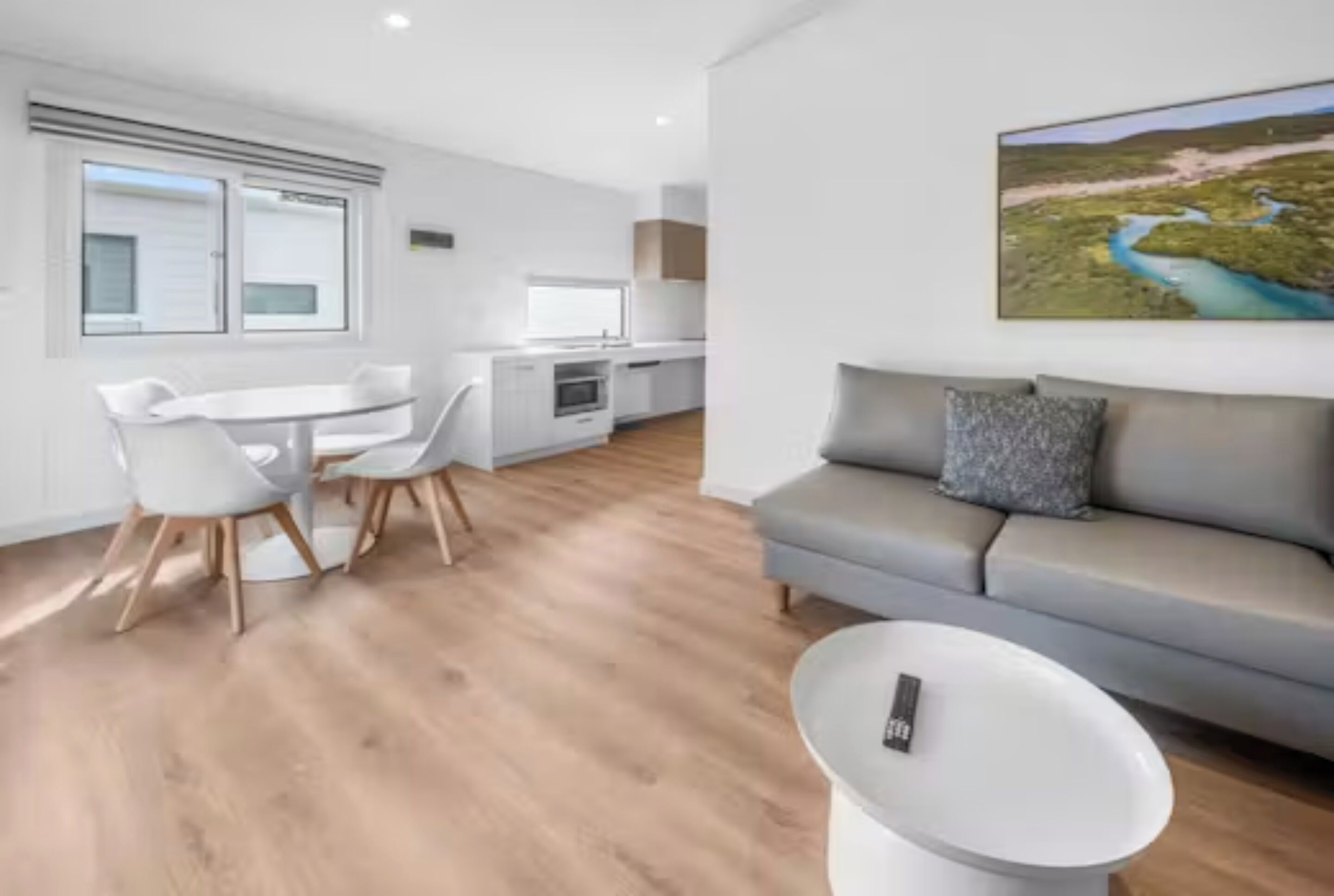 A modern living space with a dining area, kitchenette, and a sofa.