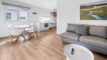 A modern living space with a dining area, kitchenette, and a sofa.