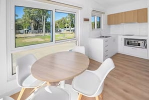 Una cocina moderna con armarios blancos, horno integrado y un amplio ventanal con vistas a una zona verde.
