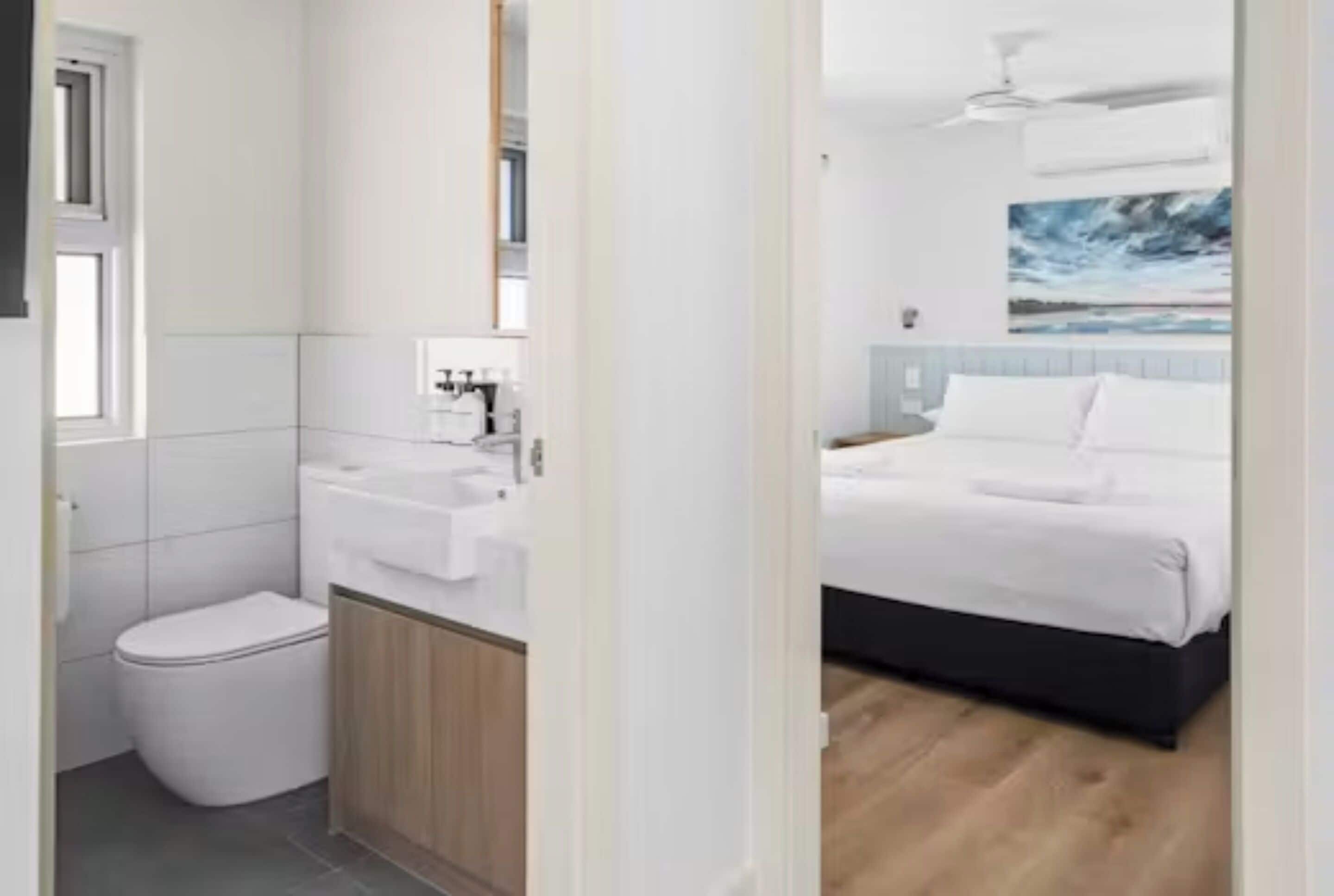 Un baño moderno con inodoro, lavamanos y espejo.