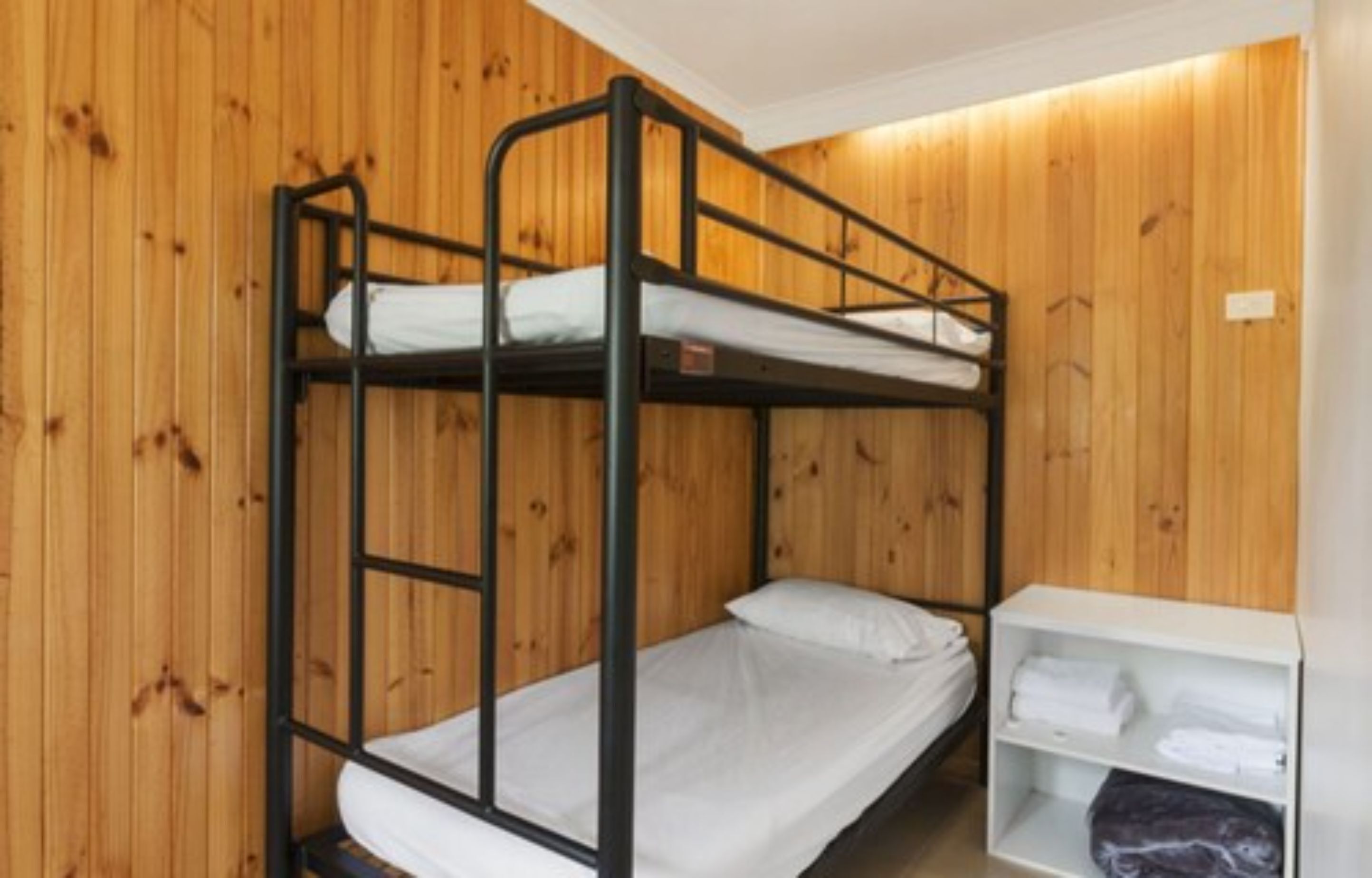 Een slaapkamer met stapelbedden, houten wanden en een witte plank met handdoeken.