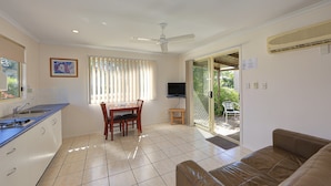 A compact living space with a kitchen, dining area, and a seating area with a sofa. - Discovery Parks - Coolwaters Yeppoon (Kinka Beach)