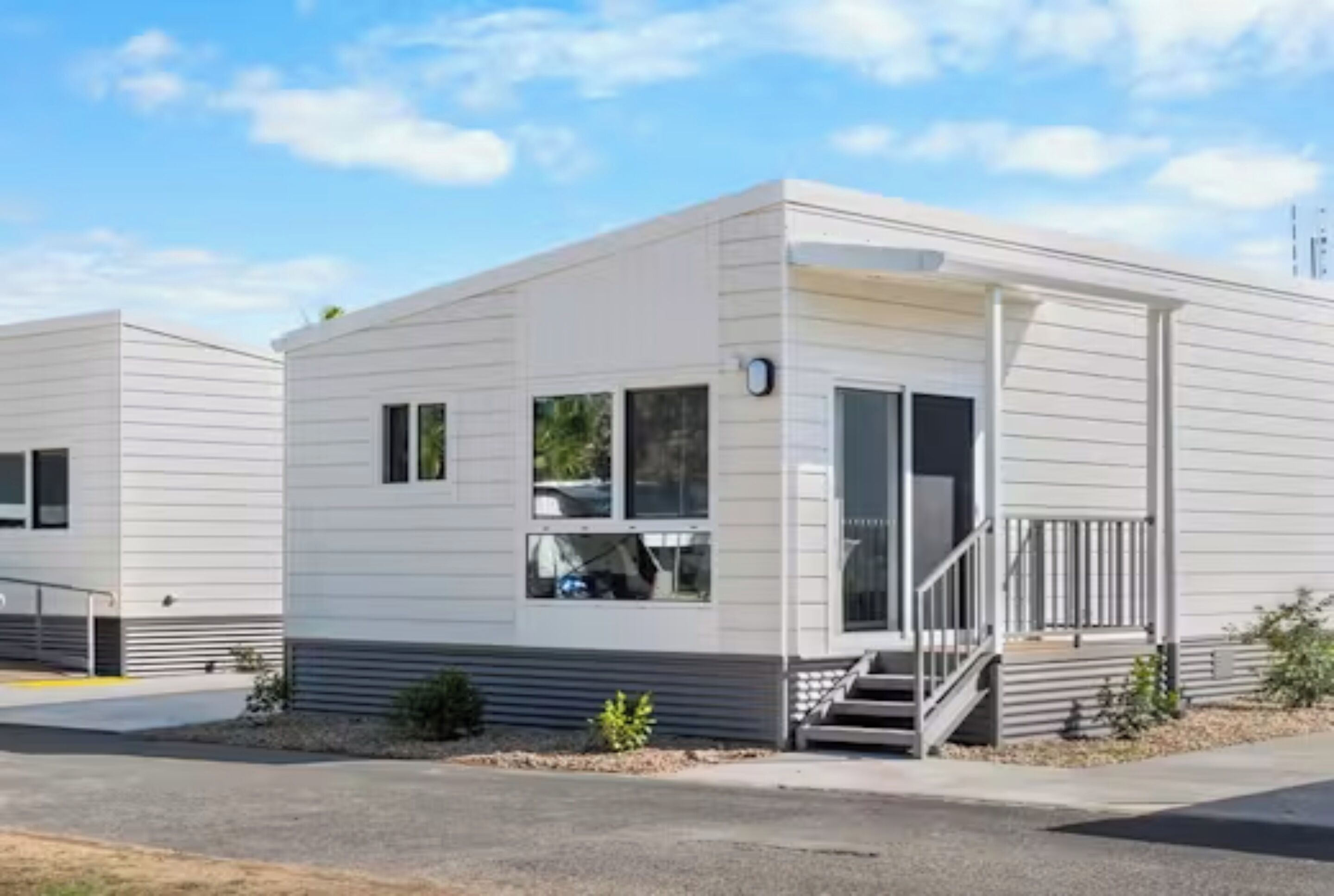 A modern, single-story mobile home with a flat roof, a front porch, and a small front yard.