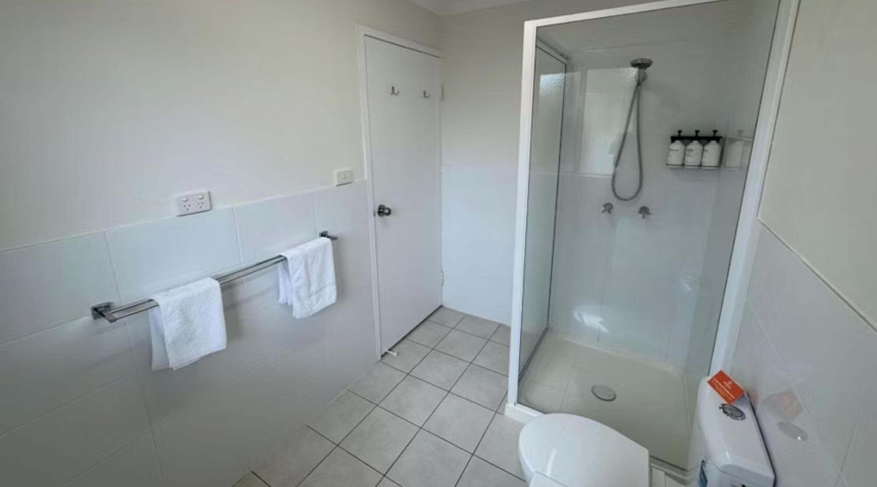 A modern bathroom with a glass-enclosed shower, a toilet, and a towel rack.