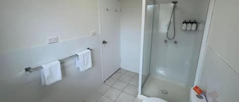 A modern bathroom with a glass-enclosed shower, a toilet, and a towel rack.