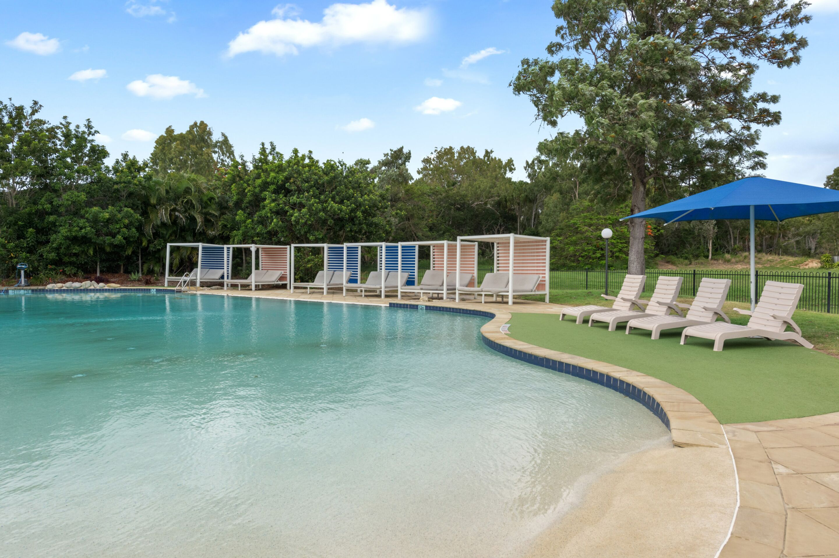 Una piscina con sillones de descanso y una zona cubierta.