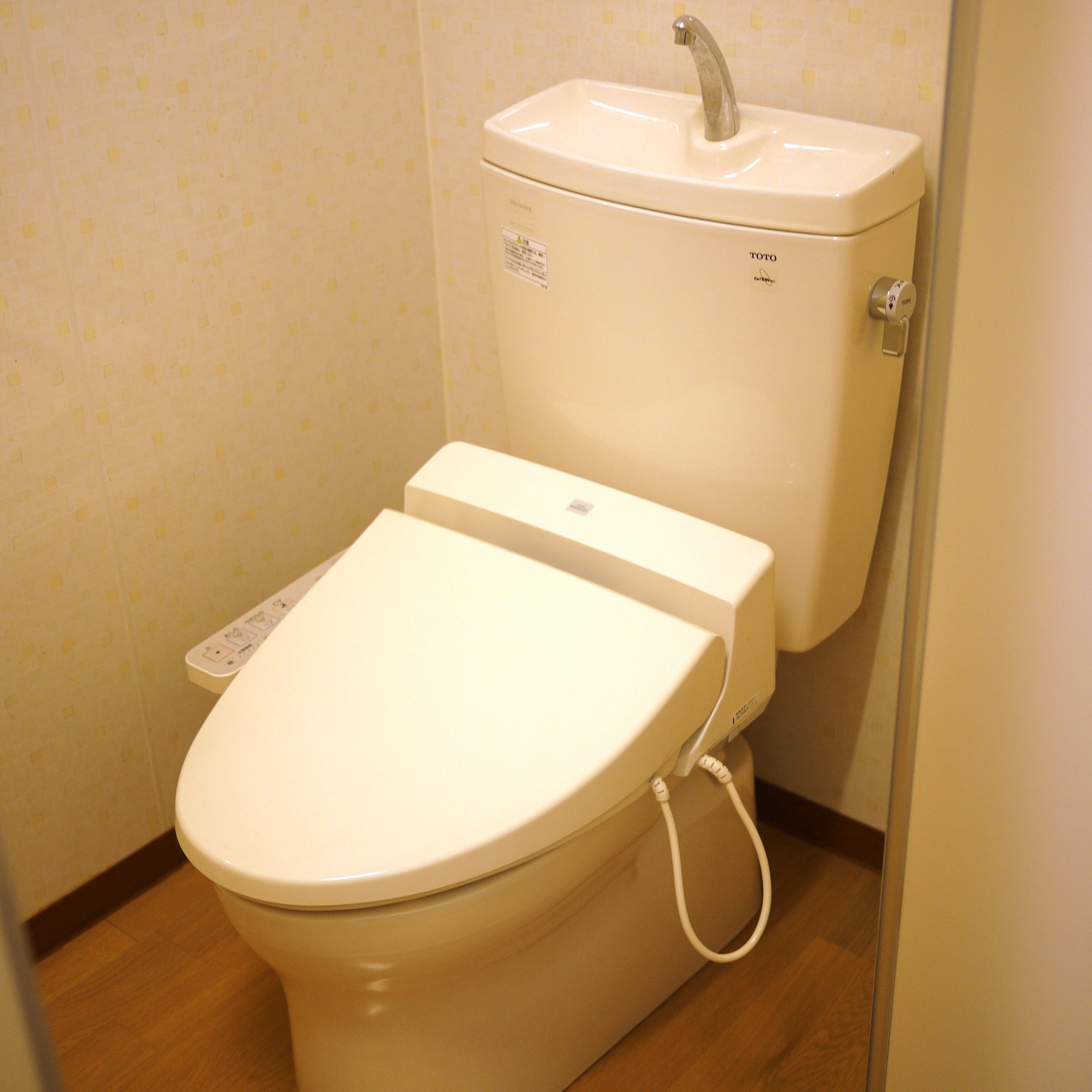 A toilet with a control panel and a wall-mounted sink.