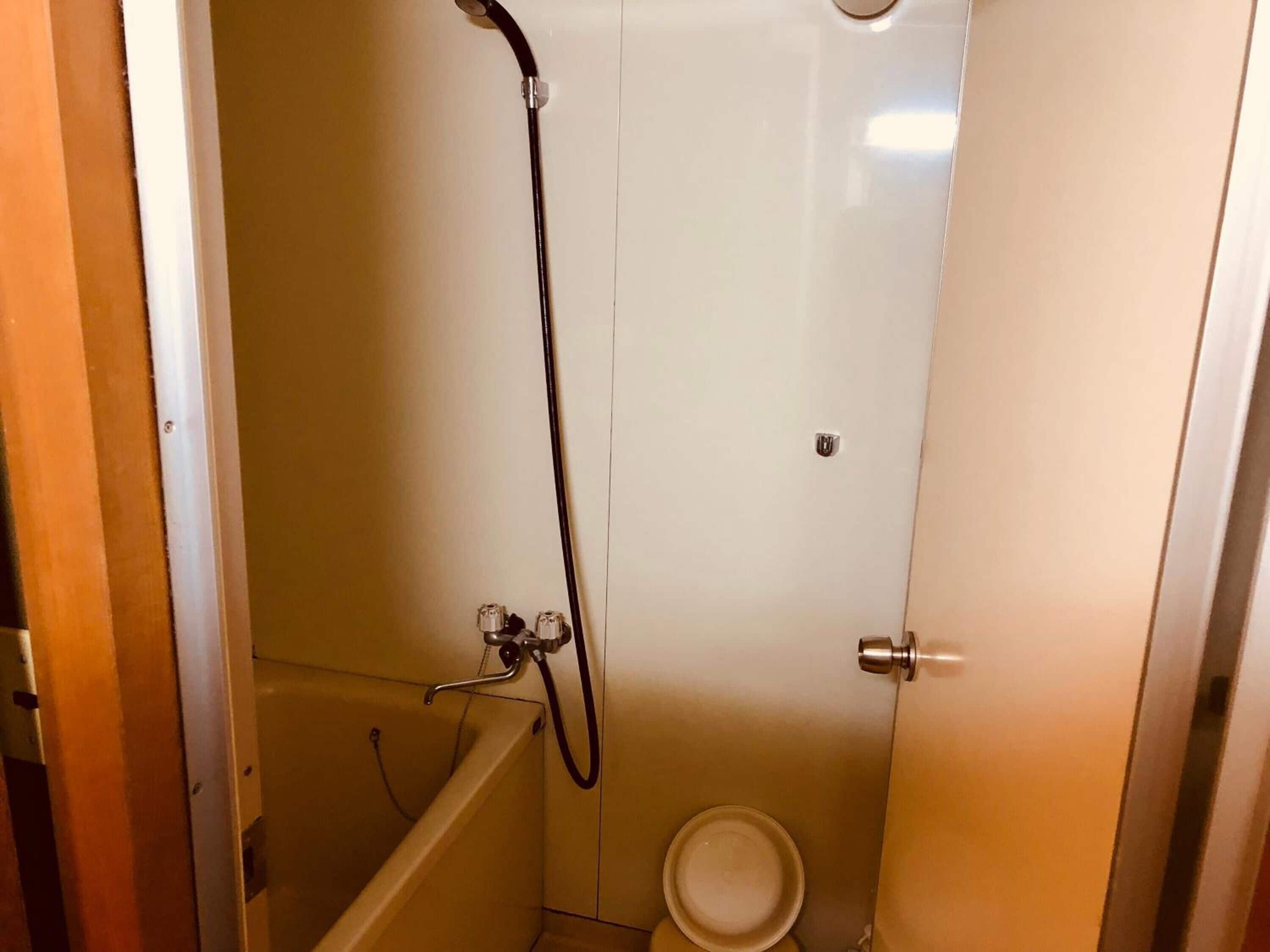 Et lille badeværelse med badekar, bruser og toilet.