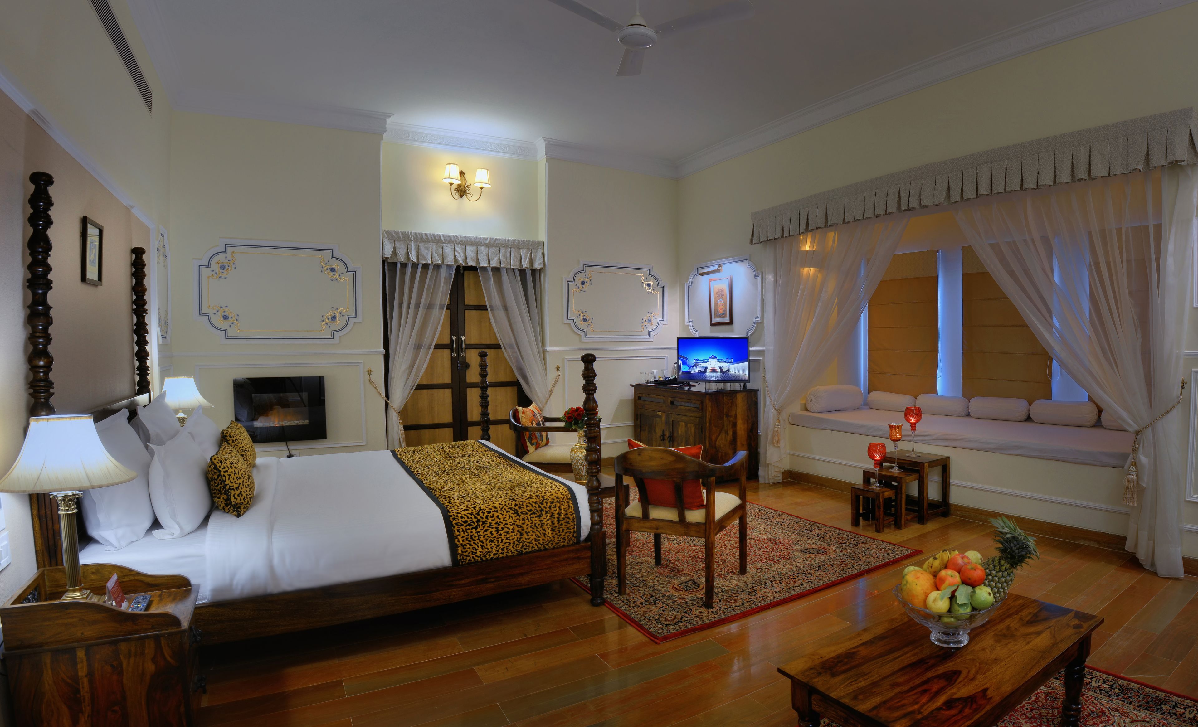 Une chambre d’hôtel avec un lit, un bureau, une télévision, un canapé et une fenêtre avec des rideaux.