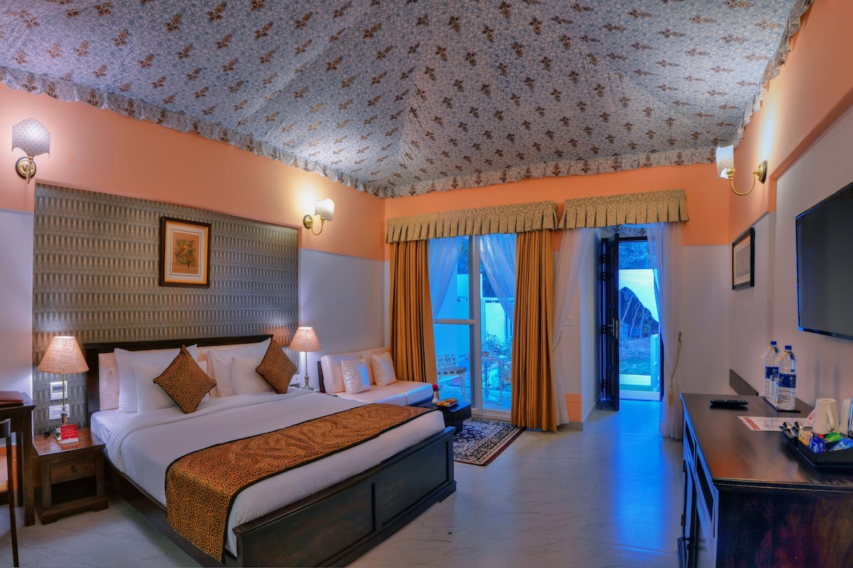 A hotel room with a large bed, two bedside tables with lamps, a TV, and a view of the outdoors.