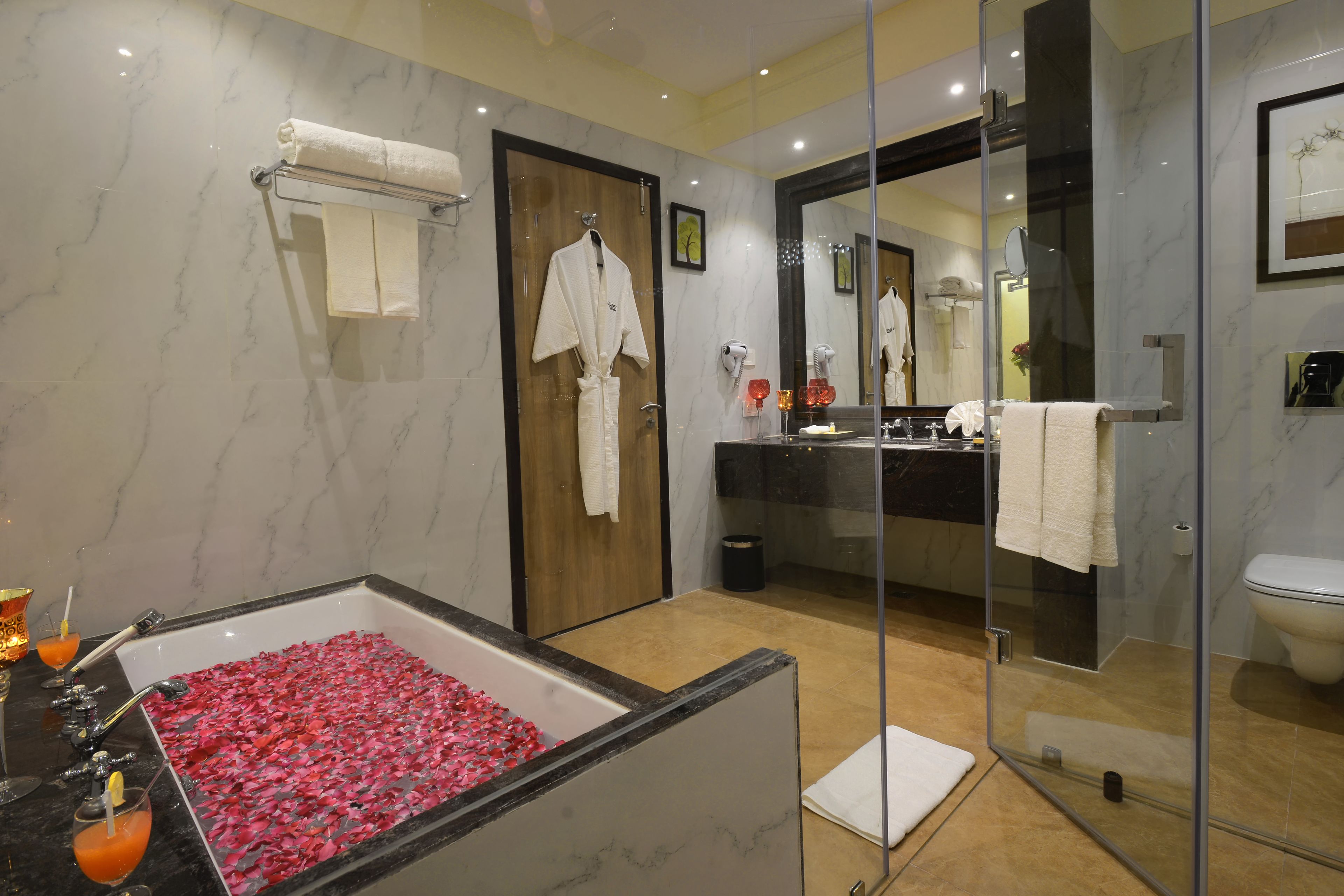 Ein modernes Badezimmer mit Marmorwaschtisch, einer begehbaren Dusche und einer mit Rosenblättern gefüllten Badewanne.