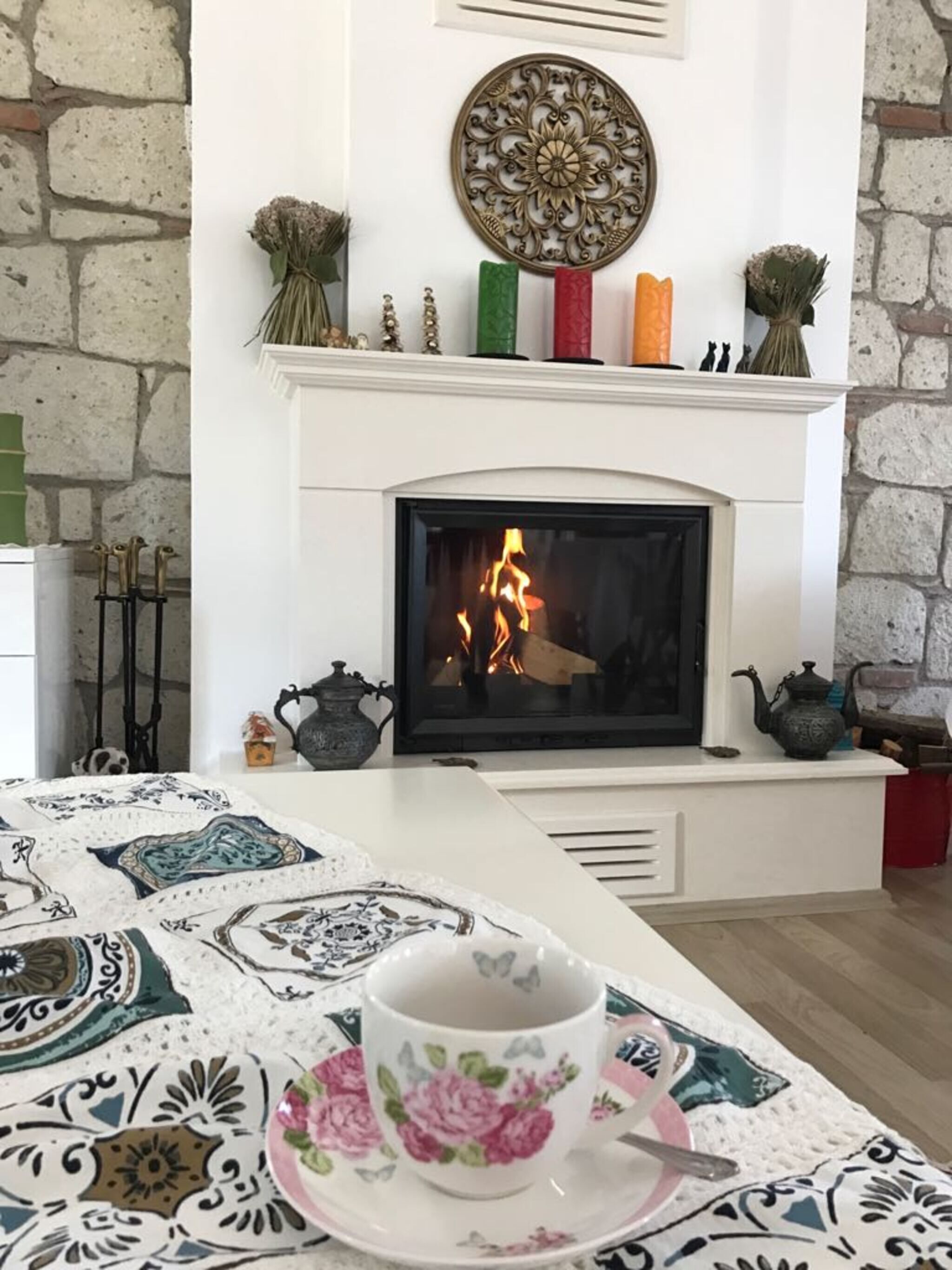 Una chimenea con fuego, un fachaleta blanco y un adorno en la pared superior.