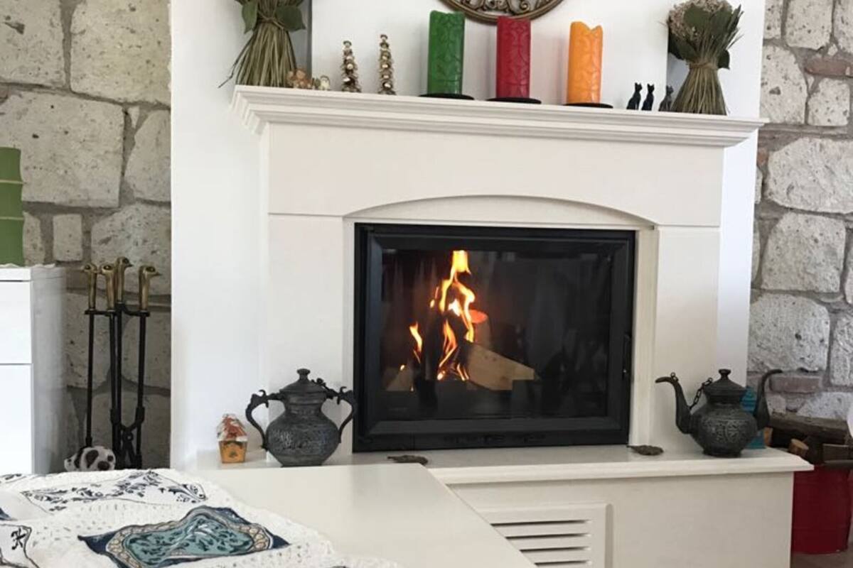 A fireplace with a fire, a white mantel, and a decorative wall piece above it.
