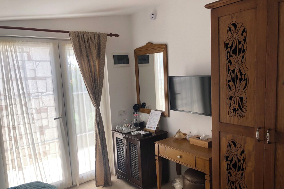 Une chambre à coucher comprenant un lit, un bureau avec un miroir, une armoire et une porte-fenêtre coulissante.