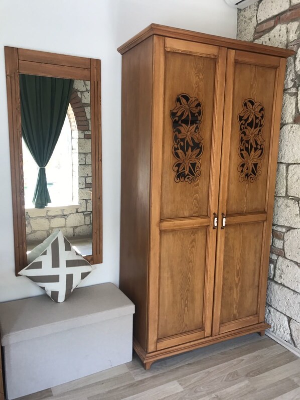 A wooden wardrobe with intricate carvings, a mirror with a green curtain, and a white bench with a geometric pillow. - Kerme Ottoman Alacati (Cesme)