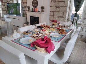 Un coin repas avec une table mise pour le repas, une cheminée et un téléviseur en arrière-plan.