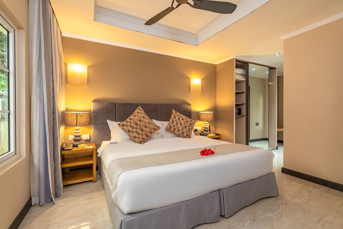A well-lit bedroom with a large bed, bedside lamps, a ceiling fan, and a walk-in closet.