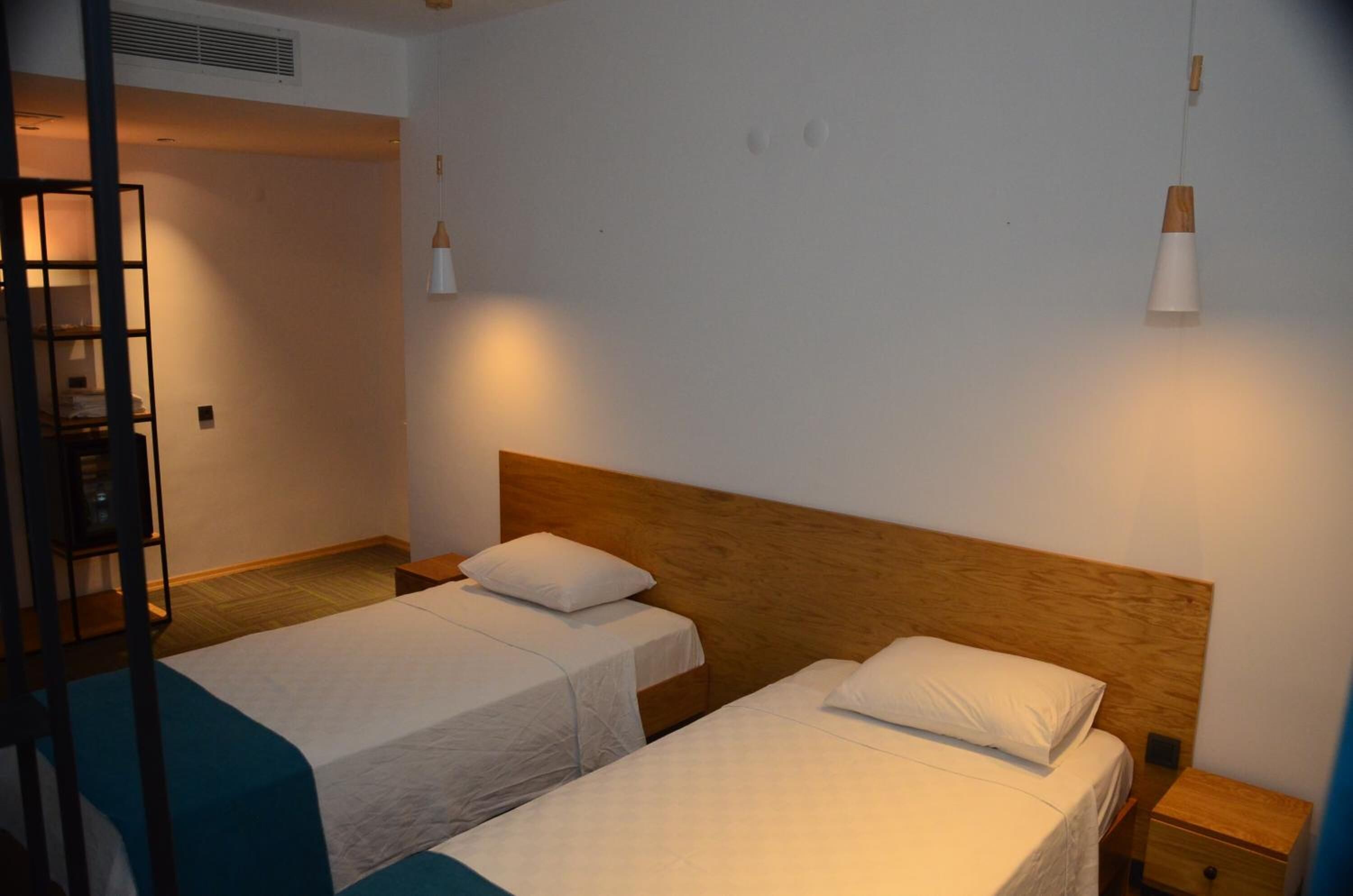Et hotelværelse med to senge, en træsenggavl, et natbord og et lille bord.