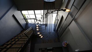 Un interior moderno con una escalera, una lámpara colgante y vistas a través de un gran ventanal.