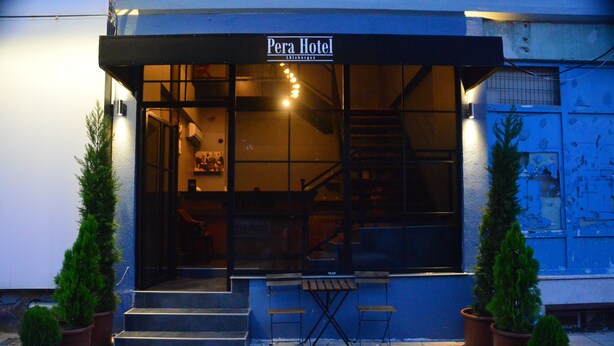 Exterior del Hotel Pera con un letrero sobre la entrada, plantas en macetas y una escalera que conduce al interior.