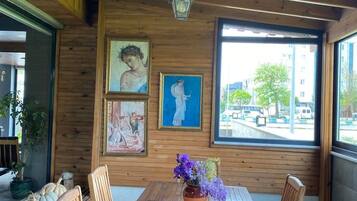 A wooden dining table with chairs, a vase with flowers, and framed artwork on the wall.