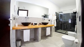 Un baño moderno con lavamanos doble, cabina de ducha con mampara de vidrio y un inodoro.