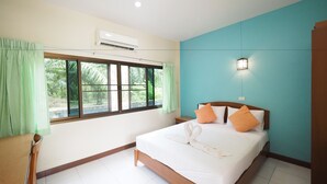 A hotel room with a bed, a nightstand, a window with curtains, an air conditioning unit, and a wall-mounted light fixture.