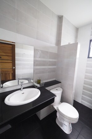 Un baño moderno con dos lavamanos, un inodoro y un espejo.