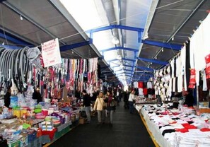 Een overdekte markt met verschillende kraampjes waar kleding en accessoires worden verkocht.