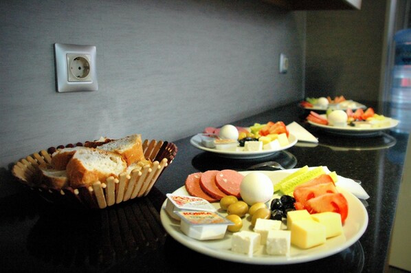 Een ontbijtbuffet met diverse kazen, vleessoorten en fruit op borden.