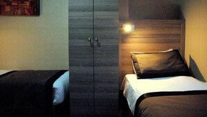 Una habitación de hotel con armario, una cama con cabecera y una lámpara fijada a la pared.