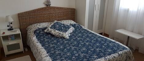 Une chambre à coucher comprenant un lit, une table de chevet, une armoire et une petite table.