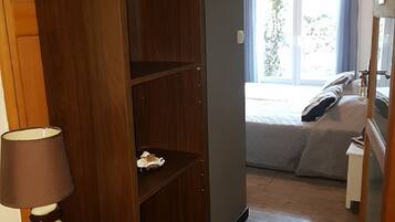 Une chambre d’hôtel avec un bureau en bois, une lampe, un lit donnant sur l’extérieur et un ventilateur de plafond.
