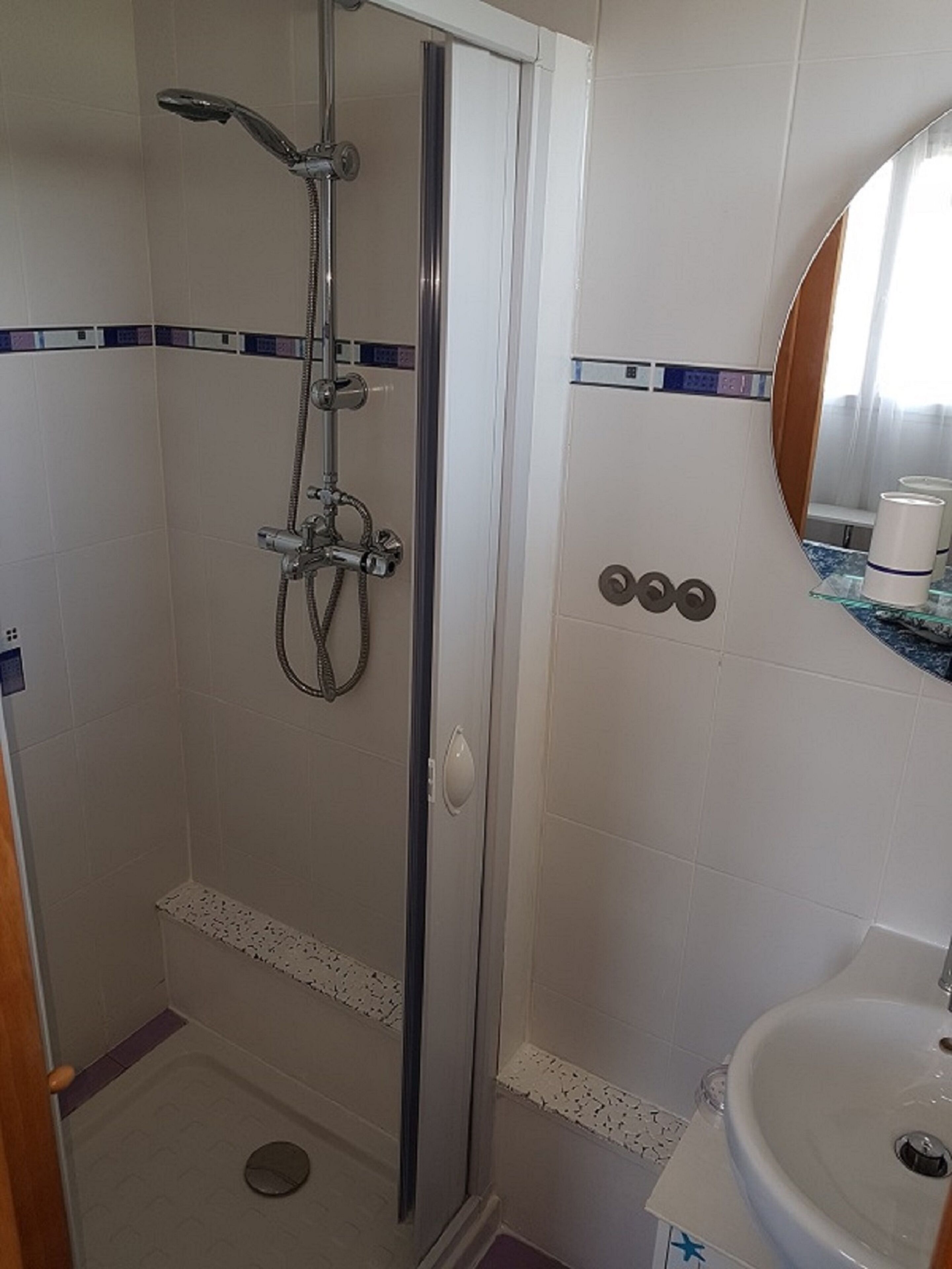 Une salle de bain avec une douche, un lavabo et un miroir.
