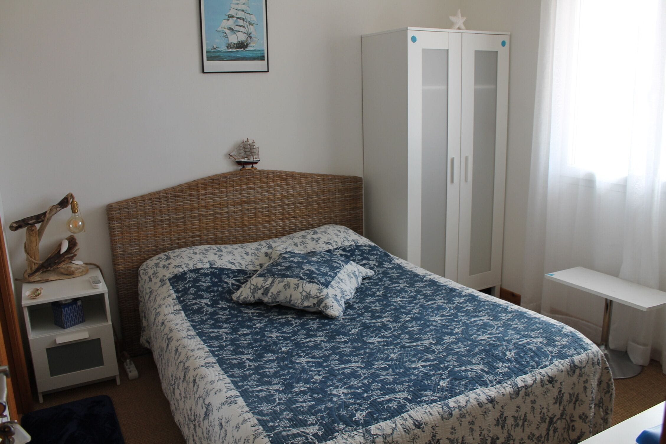 A bedroom with a bed, a wardrobe, a nightstand, and a small table.