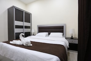 A hotel room with a large wardrobe, a bed with white linens, and two bedside tables with lamps. - 7Boys Hotel (Amman)