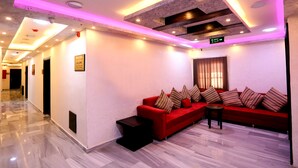 A modern hotel lobby with a red sectional sofa, a small table, and a marble floor. - 7Boys Hotel (Amman)