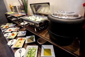 En buffet med forskellige retter og en stor gryde til højre.