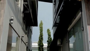 Un estrecho sendero peatonal entre dos edificios modernos con grandes ventanales y barandales de metal.